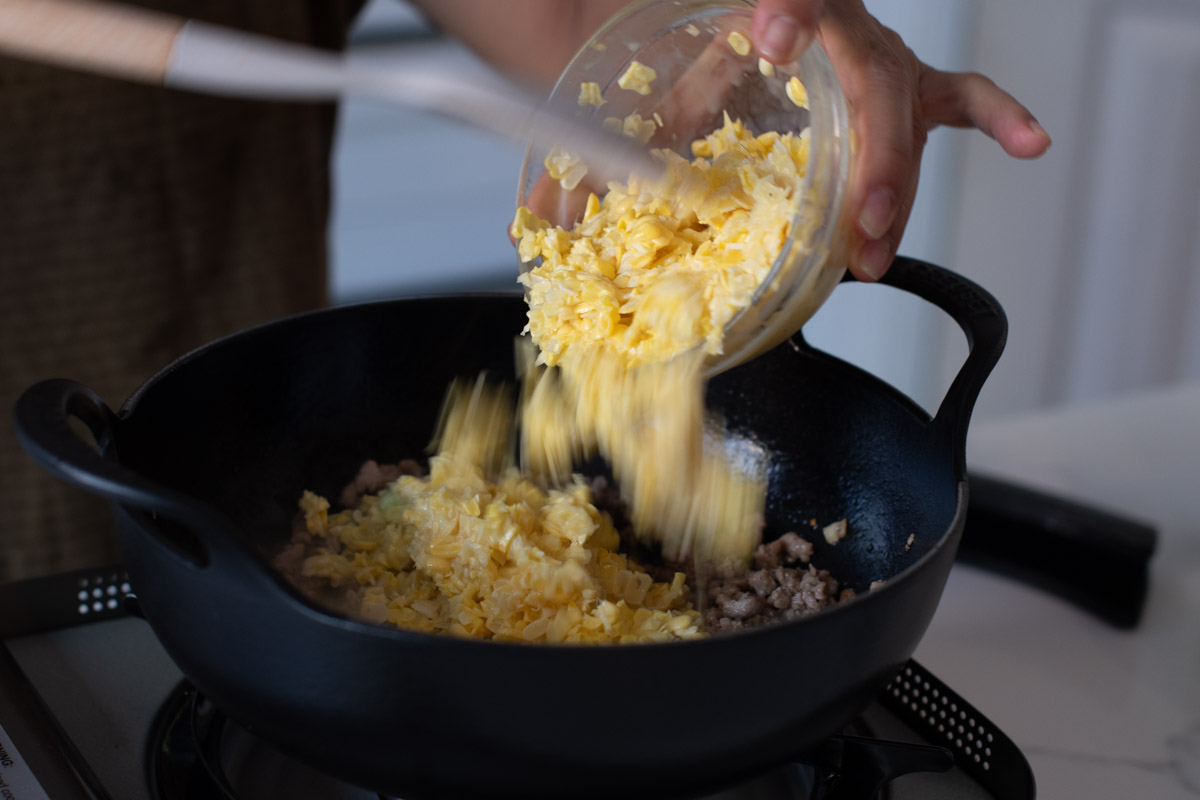 Mix in corn into wok with other ingredients.