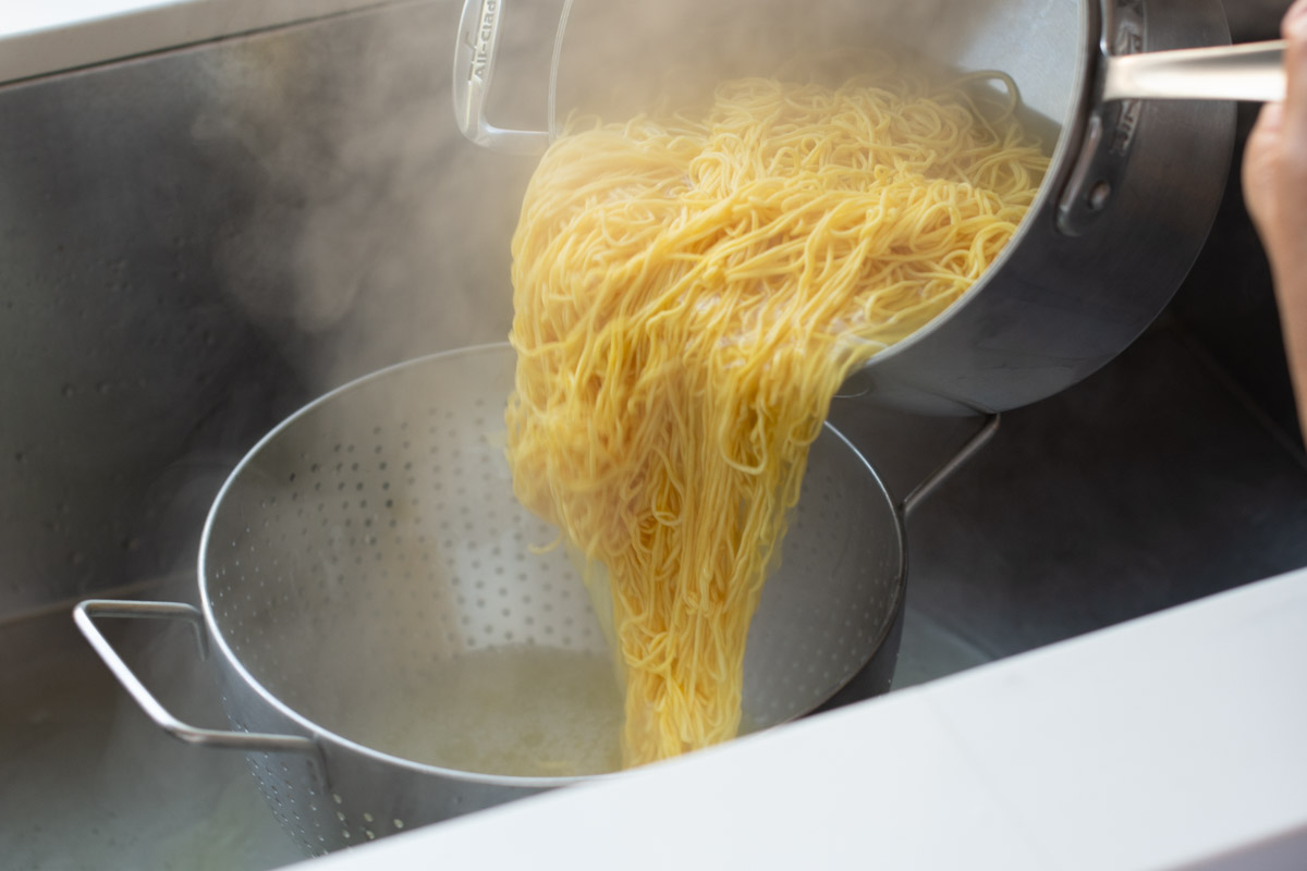 Fresh chow mein noodles draining after being rinsed for Mee Cha Jay stir-fry.